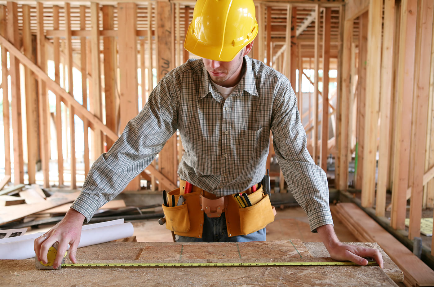 Homme qui mesure sur une table dans une construction neuve.